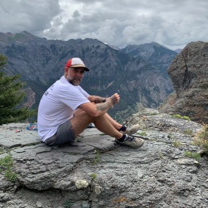 Jeff Godin sitting on the top of a mountain