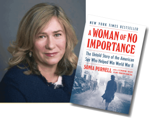 Portrait of author Sonia Purnell, a white middle age woman with shoulder length light brown hair and wearing a navy blue sweater, along side an enlarged book cover with the title in red block lettering, A Women of No Importance: The Untold Story of the American Spy Who Helped to Win World War II, and a grey/sepia photo showing a woman walking from behind down a brick street towards a soldier holding a gun