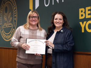 President Donna Hodge presents Linda Alvarez with a diploma on campus