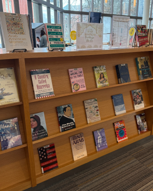 Bookshelf displaying Arab American-themed books for Arab American Heritage Month in a library.