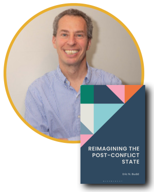 Headshot of white, middle-aged white man with short brown hair smiling and wearing a blue button down shirt with an image of a book cover entitled Reimagining the Post-Conflict State by Eric Budd 