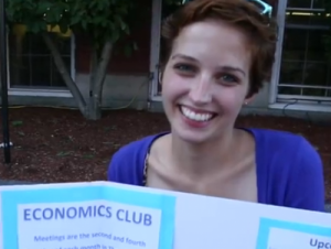 Student with a poster for the Economics Club